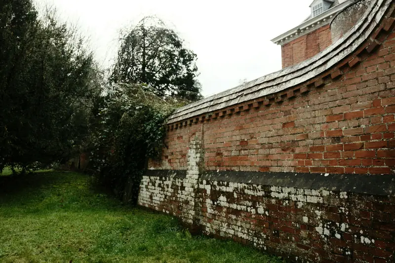 Weathered red brick garden wall curving around a lawn